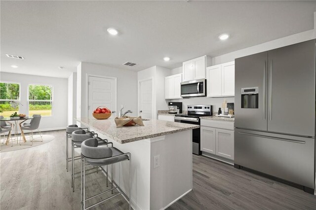 307 Holmes Blvd St, Terrytown, LA 70056 - kitchen featuring appliances with stainless steel finishes, dark wood-style floors, an island with sink, light stone counters, and recessed lighting
