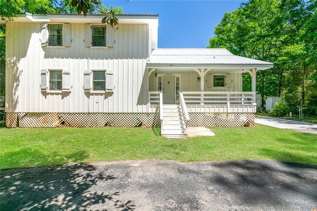 28189 Creole Rd, Lacombe, LA 70445 - view of front of house featuring a porch, a front lawn, board and batten siding, and metal roof