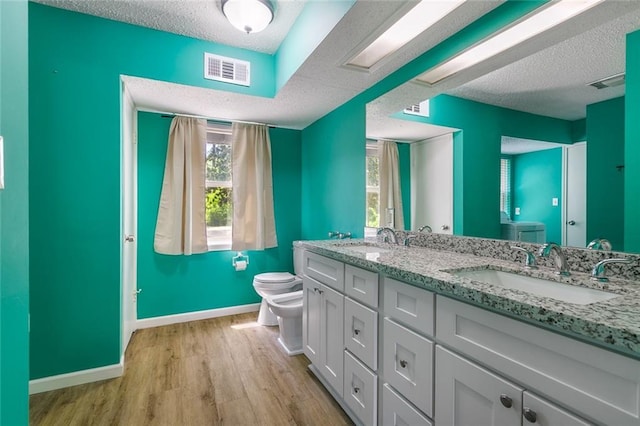 28189 Creole Rd, Lacombe, LA 70445 - bathroom featuring toilet, a textured ceiling, wood finished floors, baseboards, and double vanity