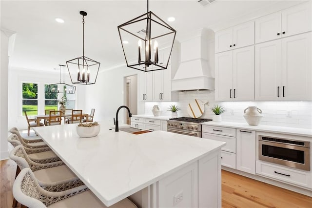 605 Northwoods Dr, Abita Springs, LA 70420 - kitchen featuring a chandelier, high end stove, light wood-style flooring, a kitchen bar, and recessed lighting