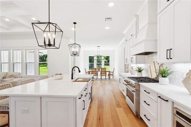 605 Northwoods Dr, Abita Springs, LA 70420 - kitchen featuring high end stove, white cabinets, custom range hood, a chandelier, and decorative backsplash