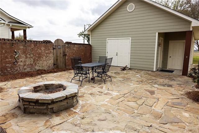 view of patio featuring a fire pit, a gate, fence, and outdoor dining area