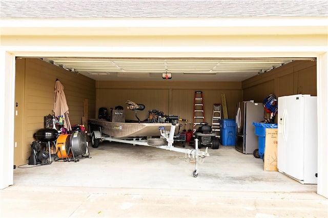 garage with white refrigerator with ice dispenser, freestanding refrigerator, and a garage door opener