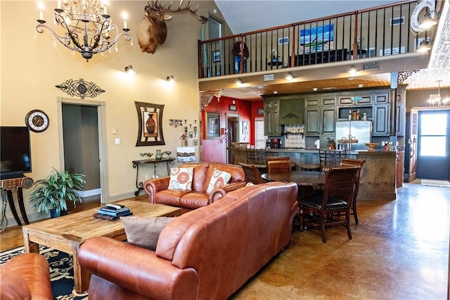 living area featuring a chandelier, a high ceiling, baseboards, and finished concrete flooring
