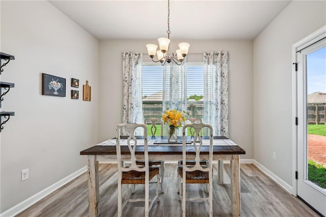 dining space with a chandelier, wood finished floors, baseboards, and plenty of natural light