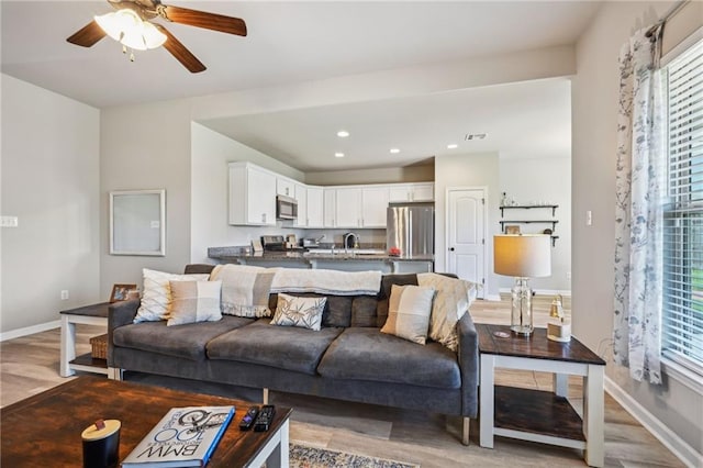 living room with light wood finished floors, baseboards, recessed lighting, and ceiling fan