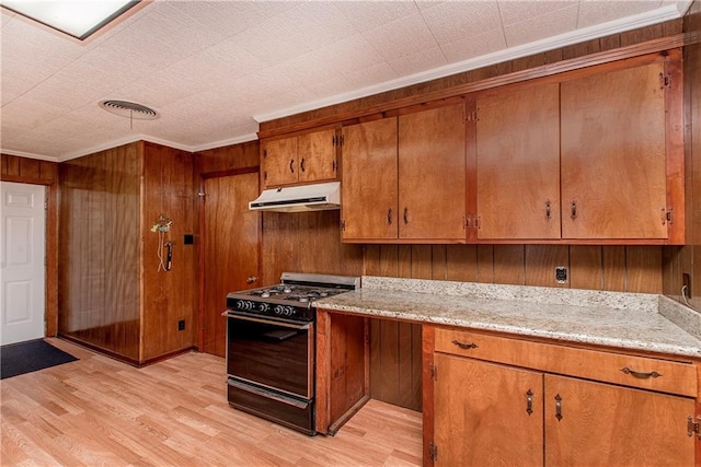 kitchen featuring gas stove, brown cabinets, under cabinet range hood, light wood-type flooring, and ornamental molding
