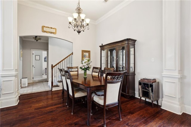 dining area featuring arched walkways, ornamental molding, wood finished floors, a chandelier, and stairway