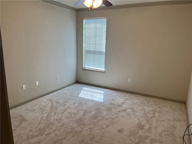 carpeted spare room featuring ornamental molding, plenty of natural light, ceiling fan, and baseboards