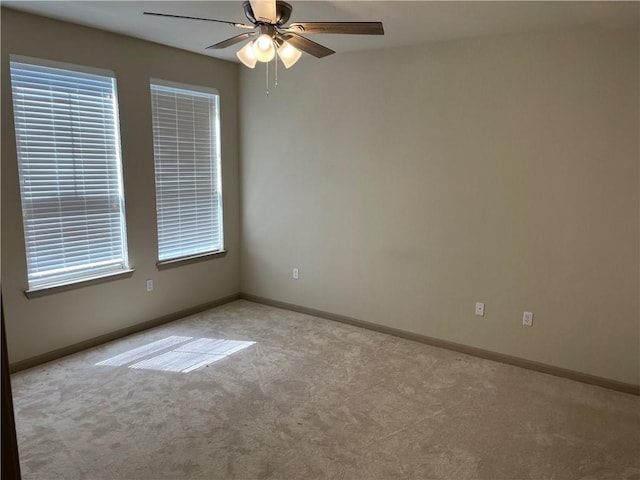 empty room featuring carpet flooring, a ceiling fan, baseboards, and healthy amount of natural light