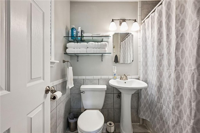 389 Hickory Dr, Slidell, LA 70458 - full bathroom featuring tile walls, toilet, a shower with shower curtain, wainscoting, and a sink