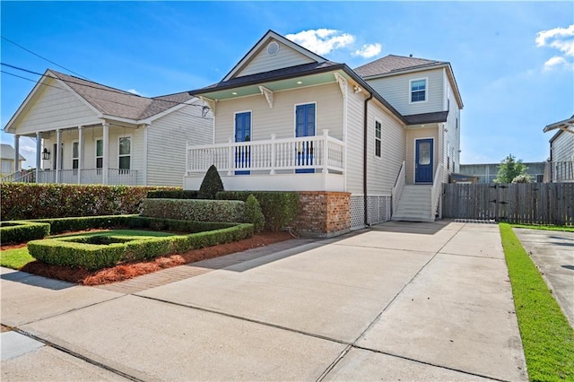 view of front of home featuring covered porch, fence, and concrete driveway