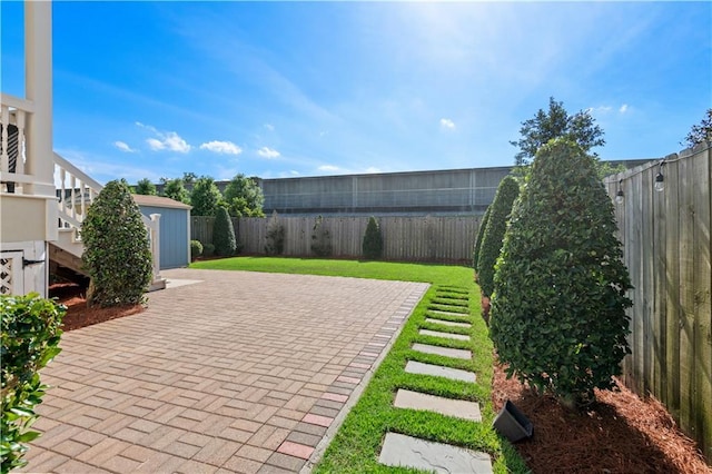 view of yard with a storage shed, a patio, and an outbuilding