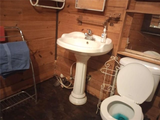 half bathroom featuring wood walls and toilet
