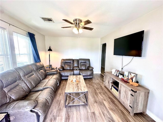 living room with arched walkways, wood finished floors, a ceiling fan, and baseboards