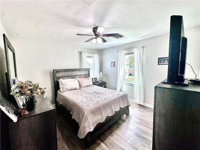 bedroom featuring a textured ceiling, hardwood / wood-style flooring, ceiling fan, and baseboards