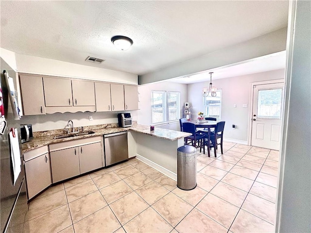 kitchen featuring a sink, appliances with stainless steel finishes, plenty of natural light, light tile patterned flooring, and a textured ceiling