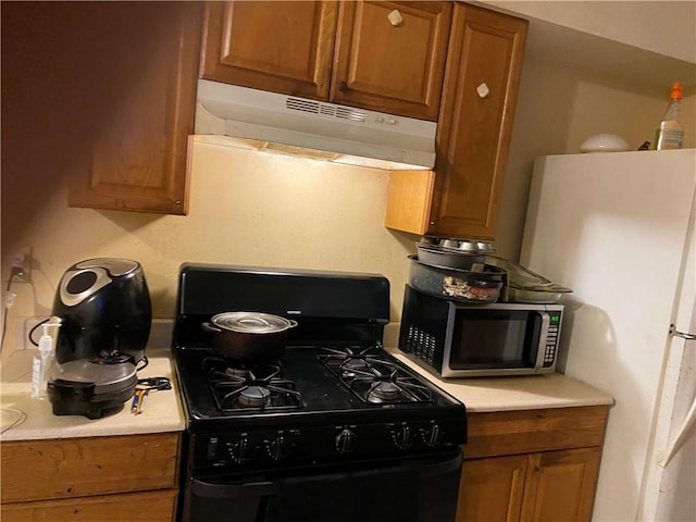 711012 Boston Dr, New Orleans, LA 70127 - kitchen featuring black gas stove, under cabinet range hood, stainless steel microwave, light countertops, and brown cabinetry