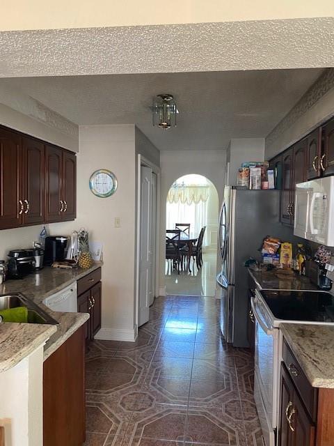 711012 Boston Dr, New Orleans, LA 70127 - kitchen featuring white appliances, baseboards, a sink, light countertops, and dark brown cabinets