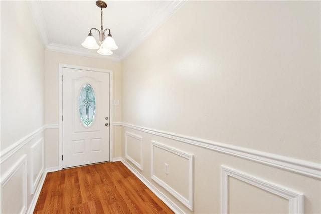 doorway to outside featuring a chandelier, ornamental molding, and light wood-style floors