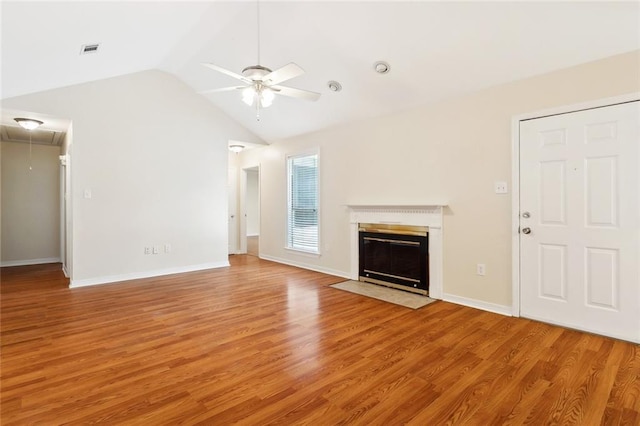unfurnished living room featuring attic access, a ceiling fan, lofted ceiling, light wood-type flooring, and a fireplace with flush hearth