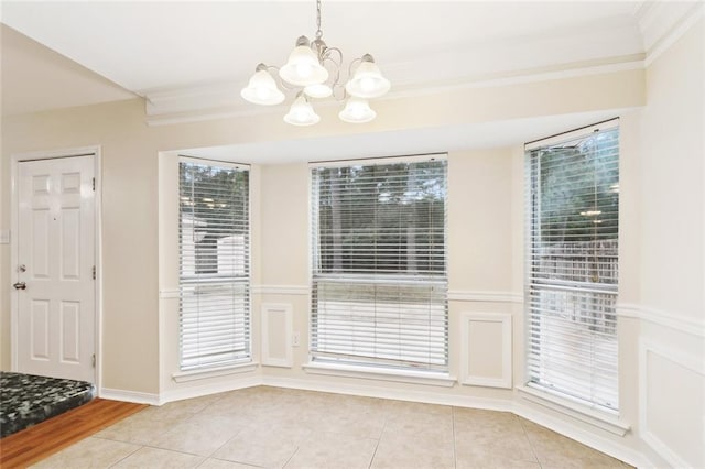 unfurnished dining area featuring a chandelier, ornamental molding, light tile patterned floors, and baseboards