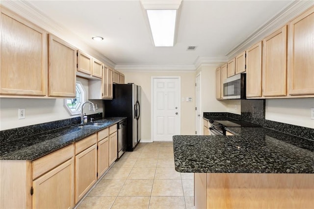 kitchen with light brown cabinetry, appliances with stainless steel finishes, a sink, light tile patterned floors, and dark stone counters