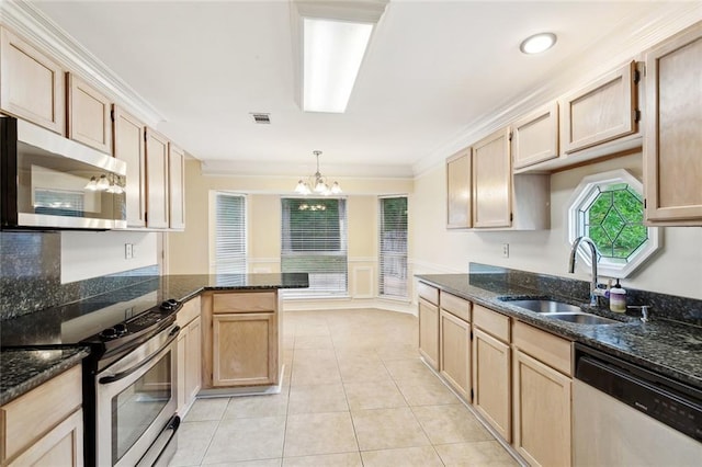 kitchen with stainless steel appliances, a sink, a chandelier, wainscoting, and crown molding