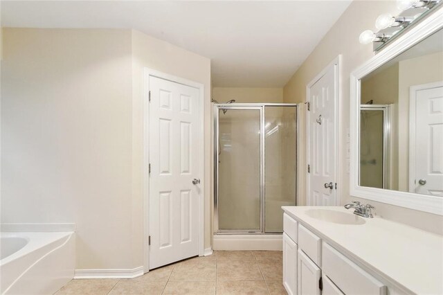 full bathroom featuring a stall shower, tile patterned floors, vanity, a bath, and baseboards