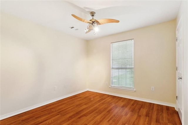 empty room with wood finished floors, baseboards, and a ceiling fan