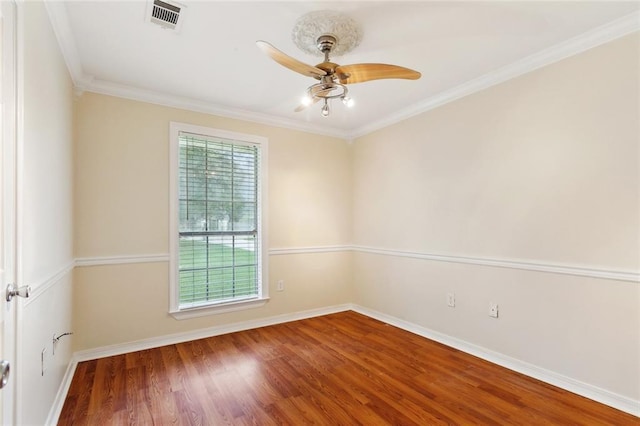 empty room featuring a ceiling fan, wood finished floors, baseboards, and ornamental molding