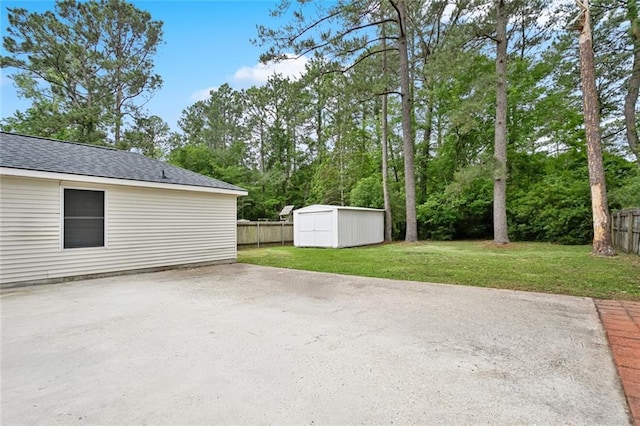 view of patio / terrace with a storage unit, an outbuilding, and view of wooded area