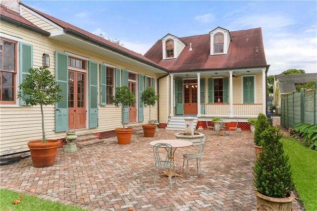rear view of house featuring entry steps, covered porch, and fence