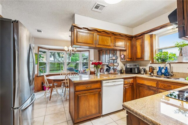 5037 Tartan Dr, Metairie, LA 70003 - kitchen with freestanding refrigerator, white dishwasher, a sink, brown cabinets, and a textured ceiling