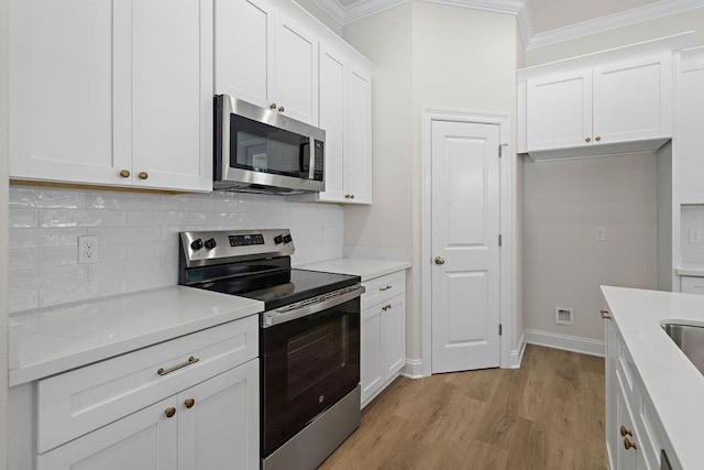 2441 Dupard St, Mandeville, LA 70448 - kitchen with appliances with stainless steel finishes, crown molding, light wood finished floors, tasteful backsplash, and white cabinets