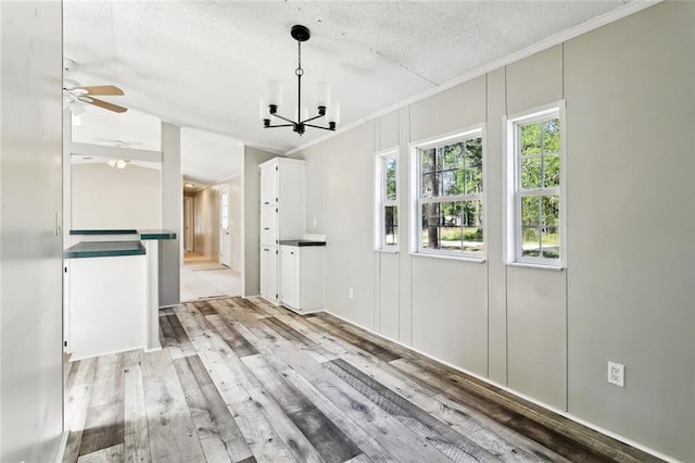 25259 Bunker St, Abita Springs, LA 70420 - unfurnished dining area with a chandelier, crown molding, light wood finished floors, a textured ceiling, and a ceiling fan