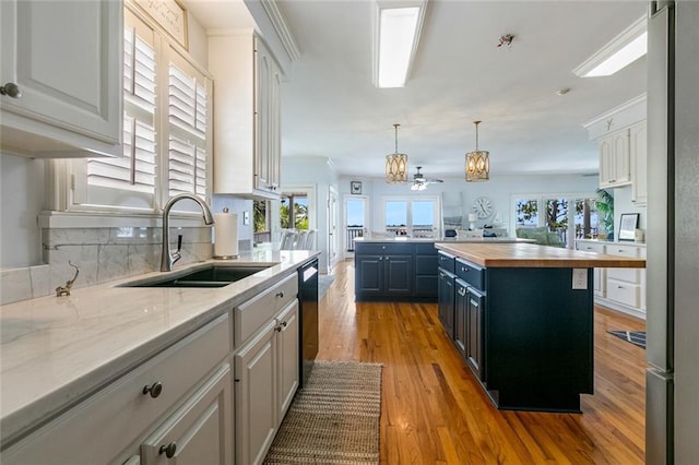 228 Marlin Dr, Slidell, LA 70461 - kitchen with a sink, butcher block countertops, decorative backsplash, wood finished floors, and dishwasher