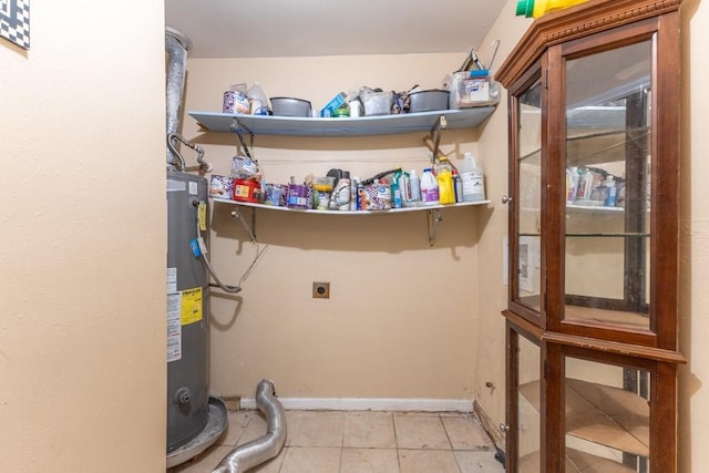 laundry room with hookup for an electric dryer, water heater, tile patterned floors, and baseboards