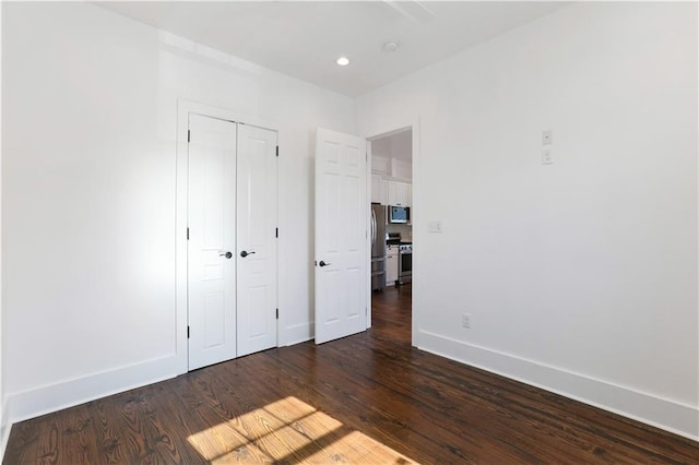 1919 N Prieur St, New Orleans, LA 70116 - unfurnished bedroom featuring freestanding refrigerator, dark wood-type flooring, baseboards, a closet, and recessed lighting