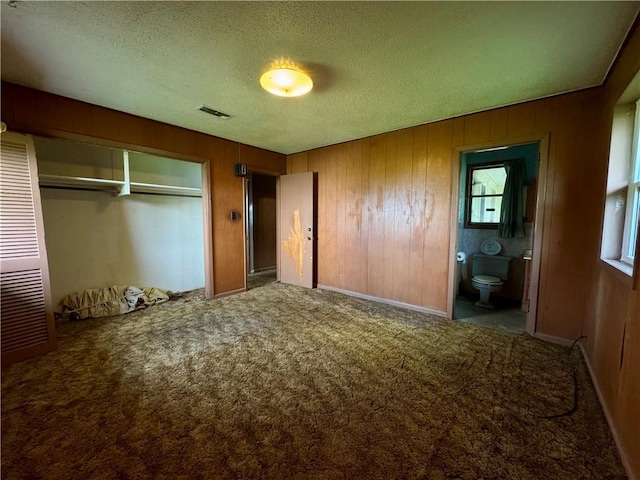 134B First St, Boutte, LA 70039 - unfurnished bedroom with carpet, a textured ceiling, a closet, wood walls, and connected bathroom