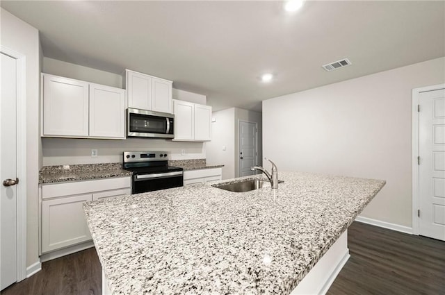24231 Gadwall Ave, Ponchatoula, LA 70454 - kitchen with appliances with stainless steel finishes, a sink, a center island with sink, dark wood-style floors, and white cabinetry