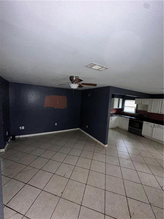 unfurnished room featuring light tile patterned floors, ceiling fan, and baseboards
