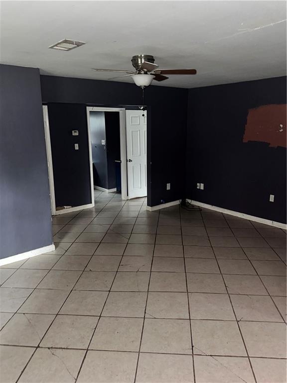 spare room featuring a ceiling fan, light tile patterned flooring, and baseboards