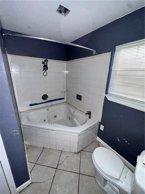 bathroom with toilet, tile patterned floors, and a combined bath / shower with jetted tub