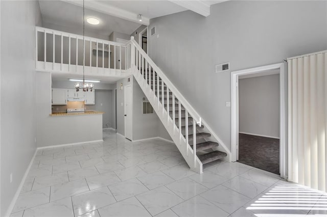 2912 Manhattan Blvd Unit 133, Harvey, LA 70058 - stairs featuring a towering ceiling, marble finish floors, a chandelier, and baseboards