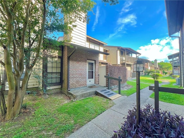 2912 Manhattan Blvd Unit 133, Harvey, LA 70058 - property entrance with brick siding, a lawn, a chimney, central AC, and a residential view