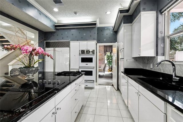 3805 3rd St, Metairie, LA 70002 - kitchen with a sink, wallpapered walls, white double oven, white cabinetry, and crown molding