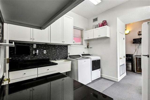 3805 3rd St, Metairie, LA 70002 - kitchen featuring independent washer and dryer, decorative backsplash, white cabinetry, light colored carpet, and baseboards