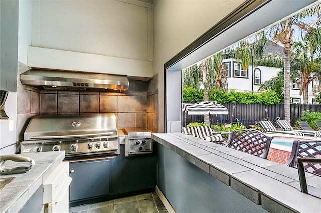 3805 3rd St, Metairie, LA 70002 - kitchen with tile countertops, range hood, backsplash, and plenty of natural light