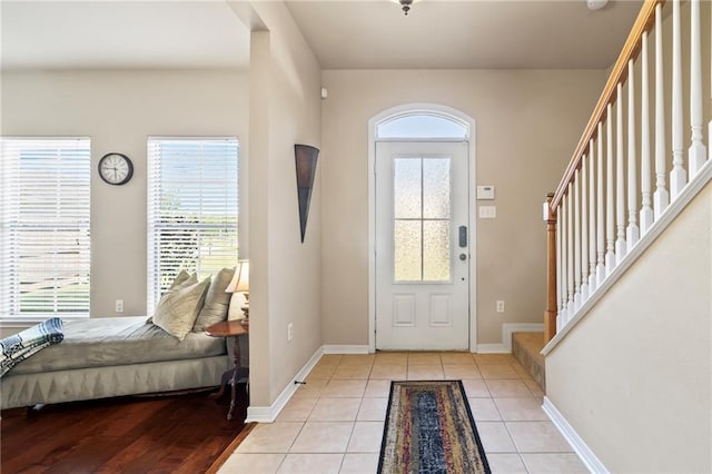 entryway featuring baseboards, stairway, and light tile patterned floors